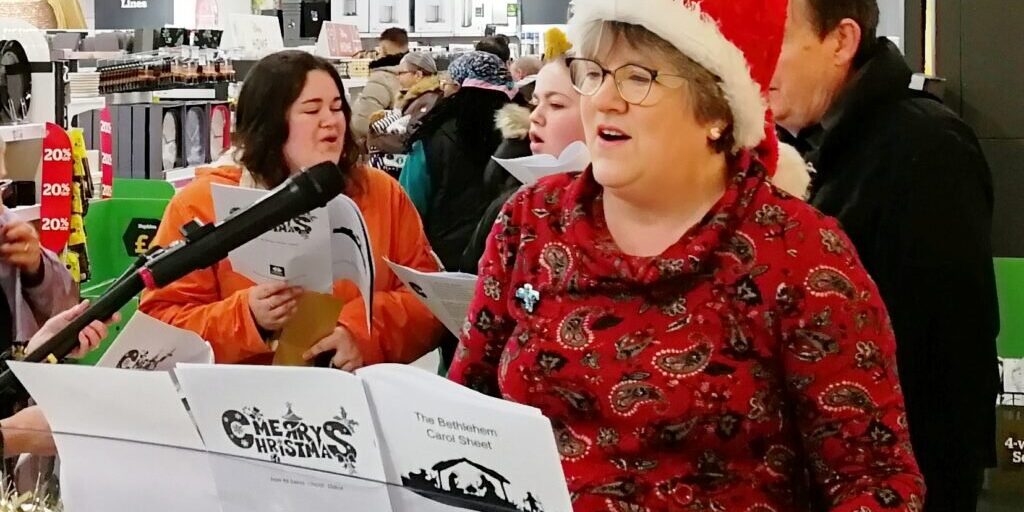Debbie Lord musician playing the piano in a shop at Christmas